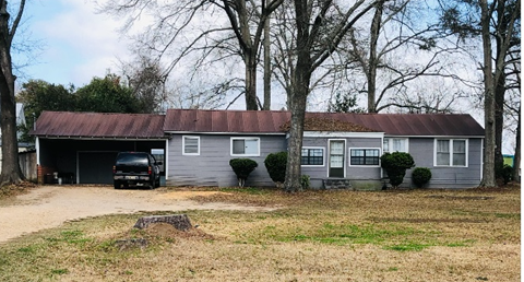 a house with a rusty roof and a truck parked in front of it