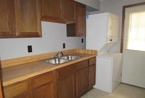 an empty kitchen with wooden cabinets and a sink