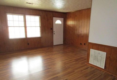 an empty living room with wood flooring and a white door