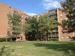 an apartment building with a green lawn and trees