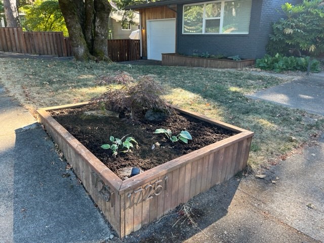 a garden in a wooden box on the side of a street