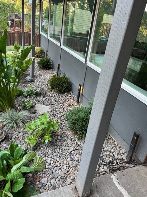the side of a house with gravel and plants next to it