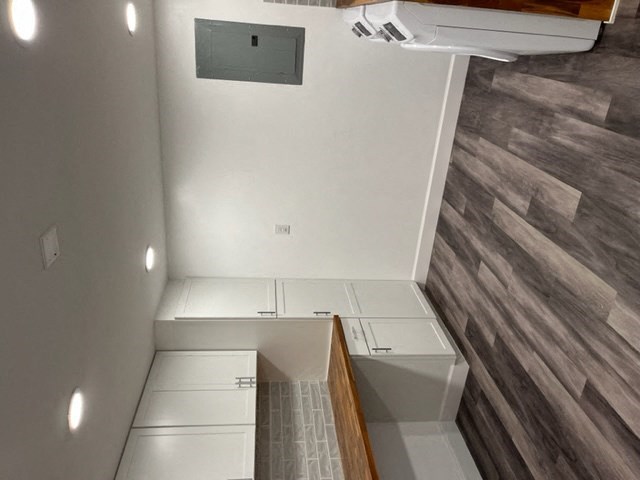 an empty kitchen with white cabinets and wood floors