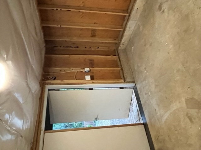 a small room with a window and a ceiling with wooden beams