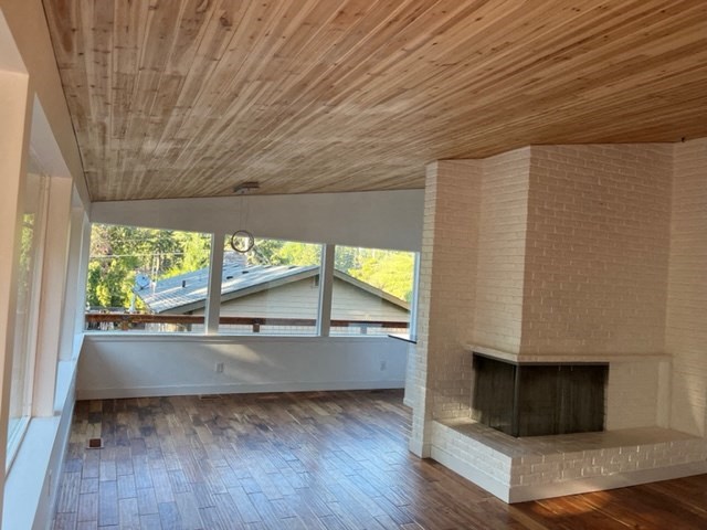 an empty living room with a fireplace and a wooden ceiling