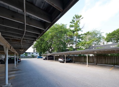 A parking lot with cars parked under a wooden canopy.