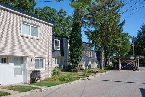 A residential street with houses on both sides and a car parked in the driveway.