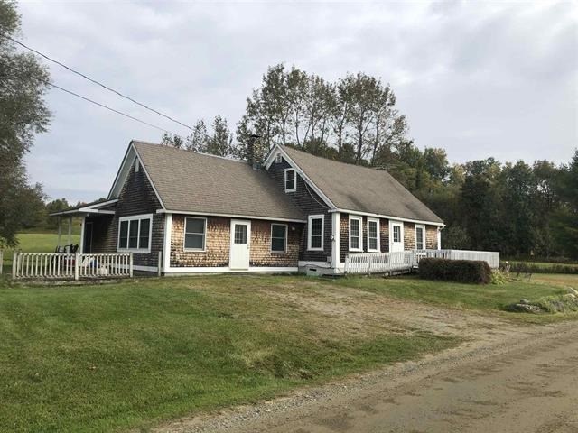 a house with a white fence in front of a field
