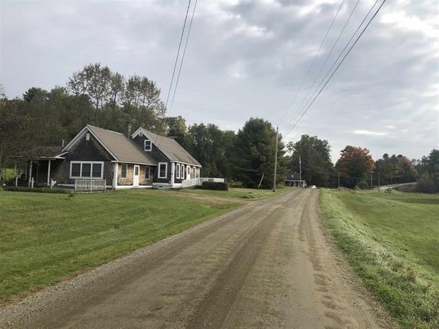 a house on the side of a dirt road