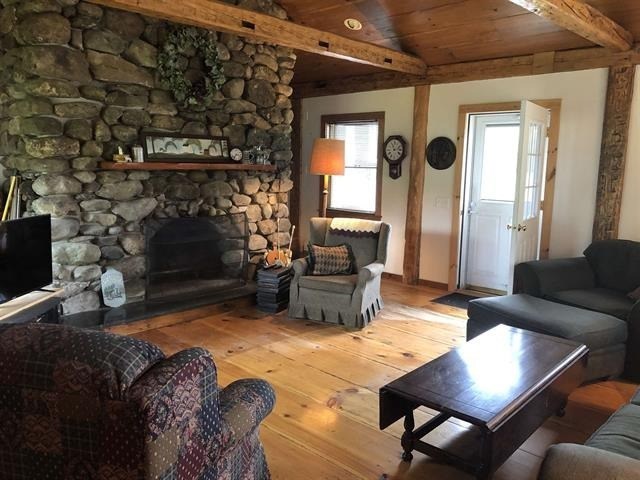 a living room with a stone fireplace and wooden floors