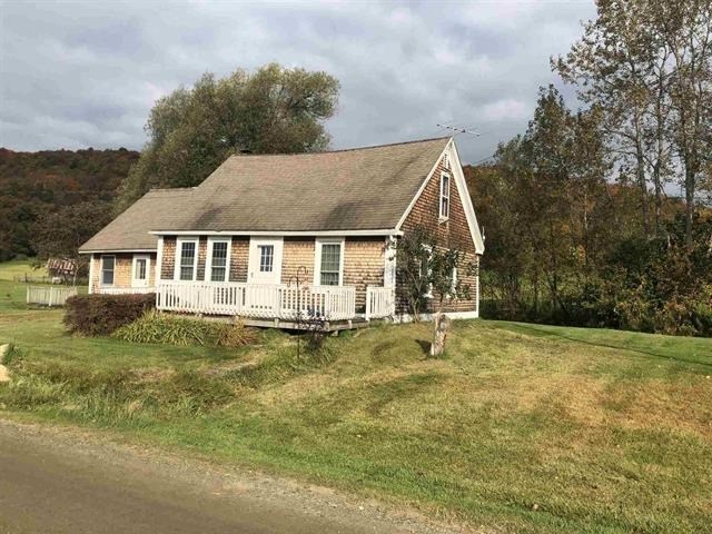 a small house on a hill next to a road