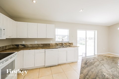 A kitchen with white cabinets and a marble countertop.