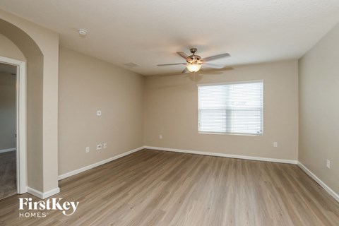 A spacious room with a ceiling fan and light fixture.