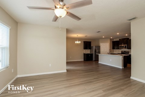 A spacious living room with a kitchen in the background.