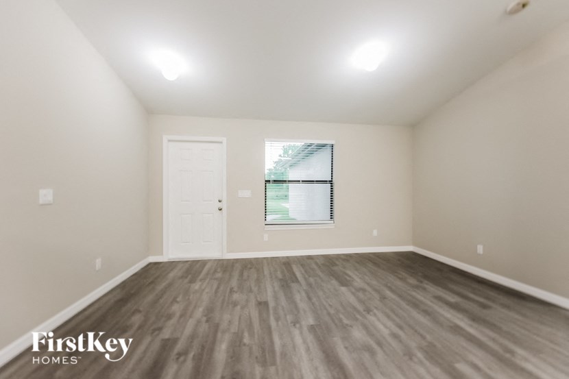 A room with wooden flooring and a window with blinds.