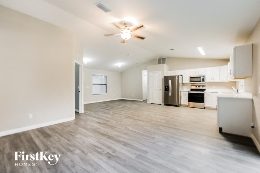 A spacious, empty room with wood flooring and a ceiling fan.