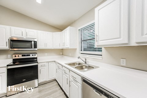 A kitchen with white cabinets and a stainless steel dishwasher.