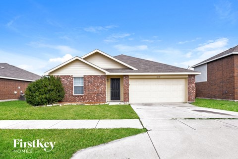a brick house with a white garage door and grass