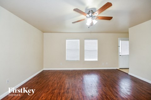 an empty living room with wood floors and a ceiling fan