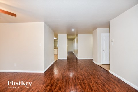 an empty living room with wood flooring and white walls