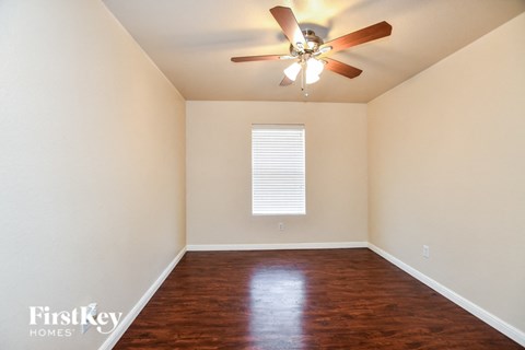 a empty room with a ceiling fan and wood floors