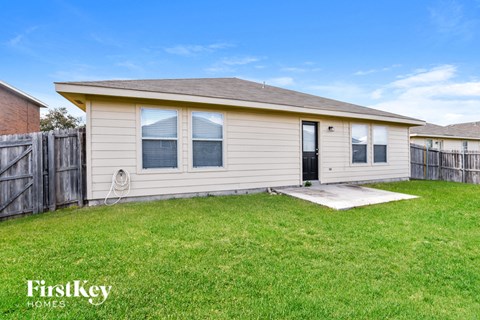 a small white house with a yard and a wooden fence