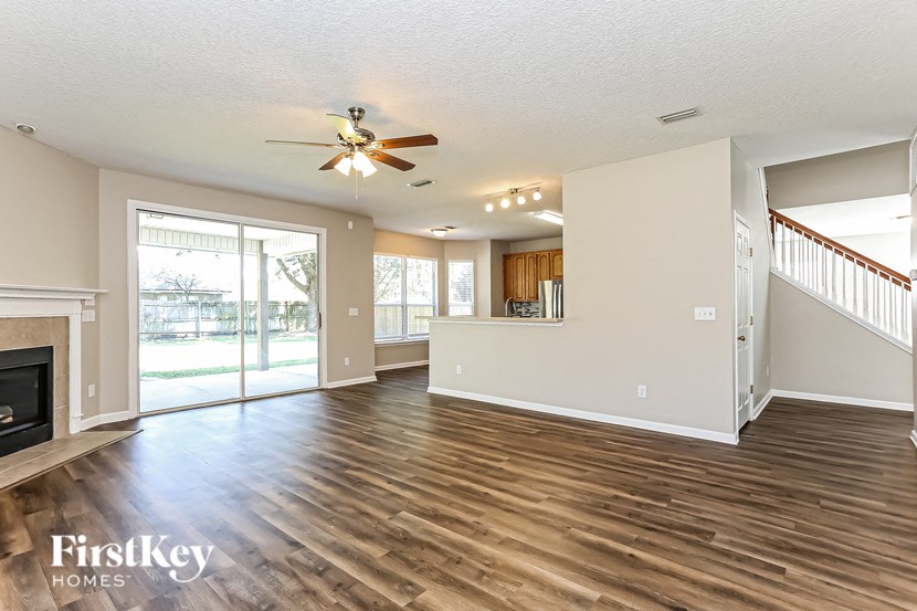A spacious living room with wood flooring and a ceiling fan.
