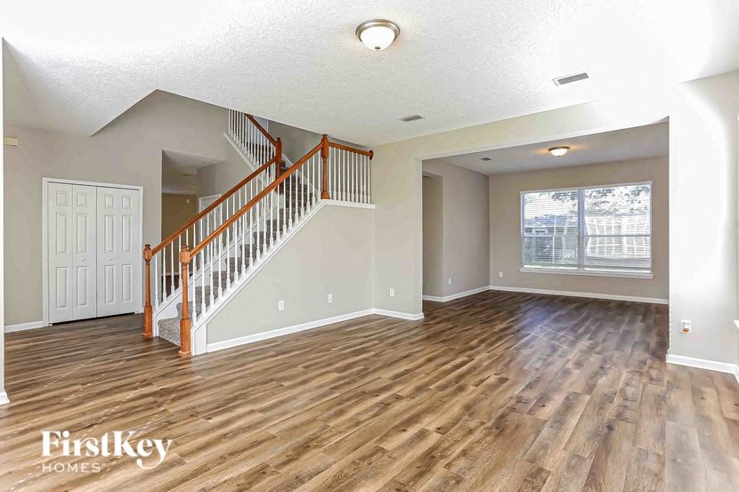 A spacious room with wooden floors and a staircase leading to another level.