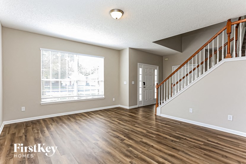 A spacious room with wooden floors and a staircase.