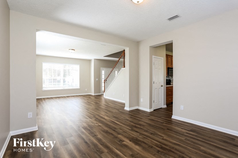 A spacious living room with wooden floors and a staircase leading to the upper level.