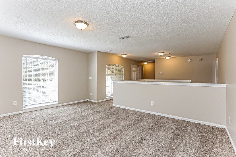 A spacious room with a carpeted floor and a large window.