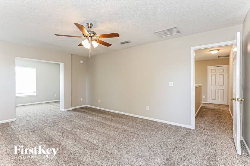 A spacious room with a ceiling fan and carpeted floor.