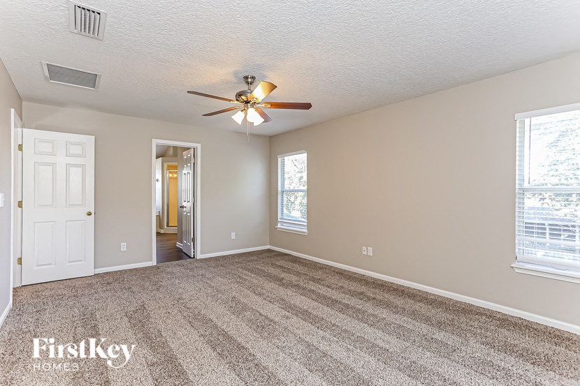 A room with a carpeted floor and a ceiling fan.