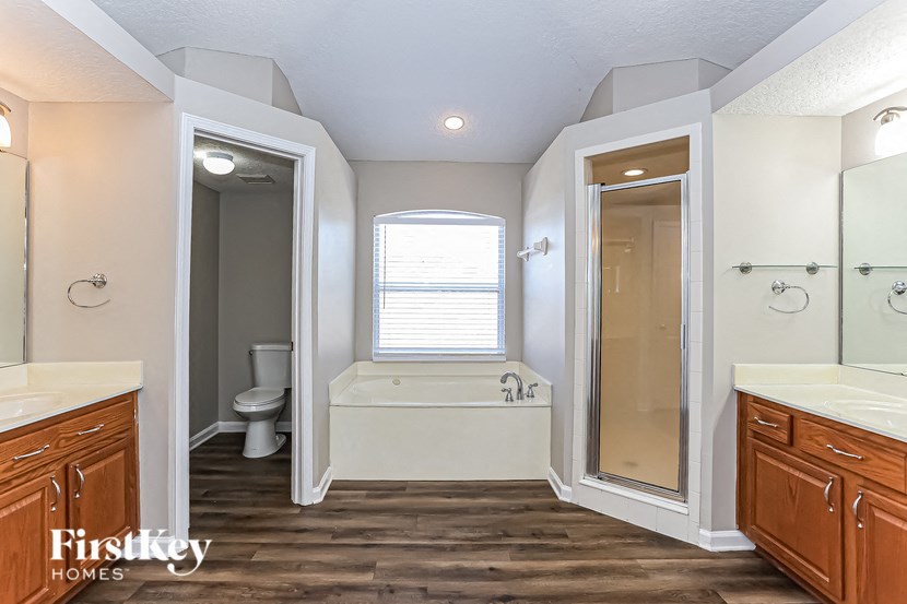 A large, well-lit bathroom with a tub, toilet, and sink.