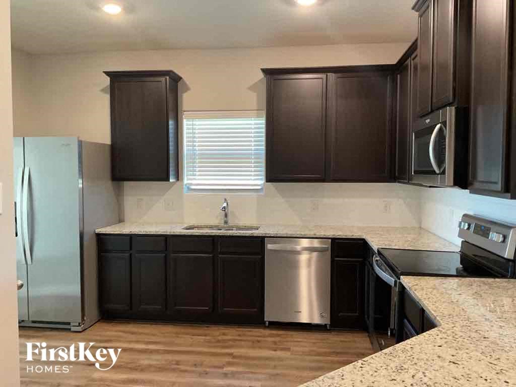 A kitchen with dark brown cabinets and a granite countertop.