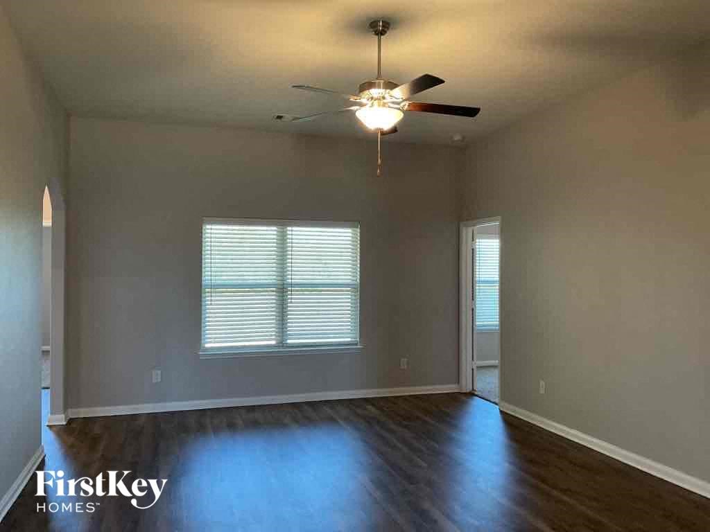 A room with a ceiling fan and a window with blinds.