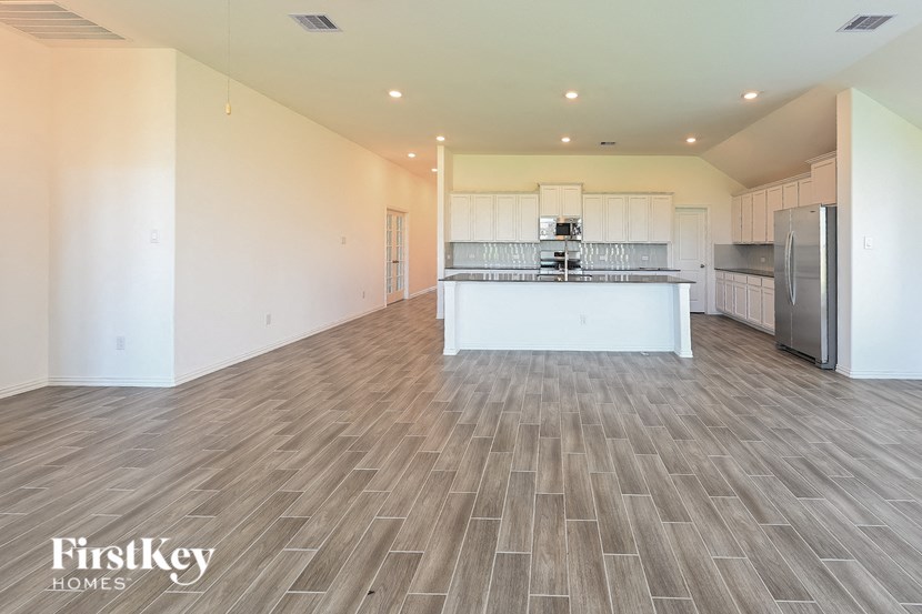 an open kitchen and living room with a stainless steel refrigerator