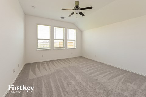 a spacious living room with carpet and a ceiling fan