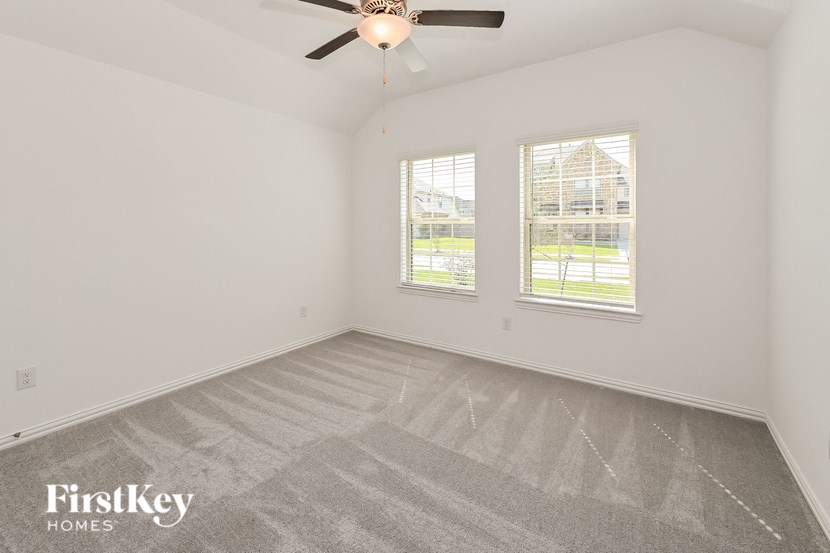 the living room of an empty house with a ceiling fan and two windows