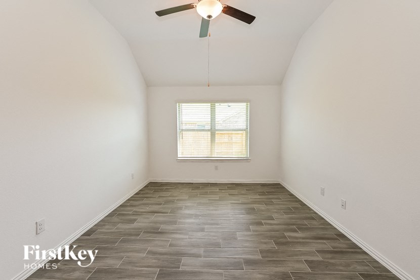 an empty room with a ceiling fan and a window