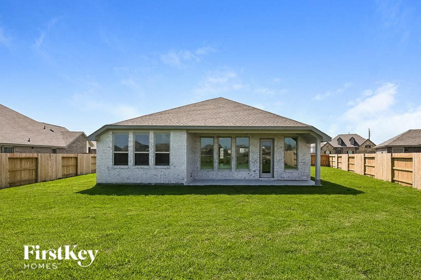 a white brick house with a yard and a wooden fence