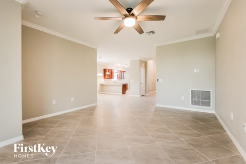 the spacious living room with tile flooring and a ceiling fan