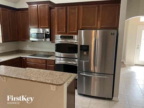 A kitchen with a stainless steel refrigerator and wooden cabinets.