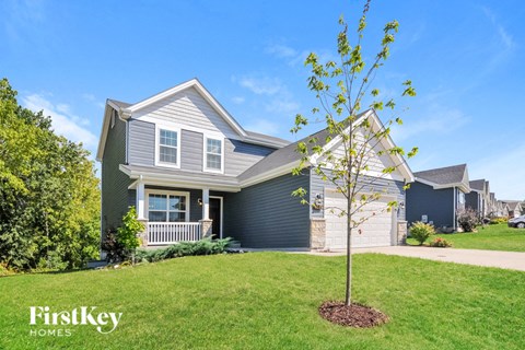 A tree is planted in a flower bed in front of a house.