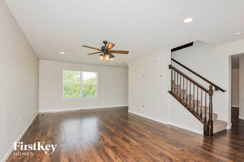 A spacious room with a wooden floor and a ceiling fan.