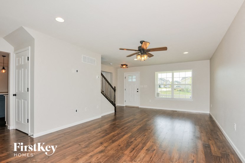 A spacious room with wooden floors and a ceiling fan.