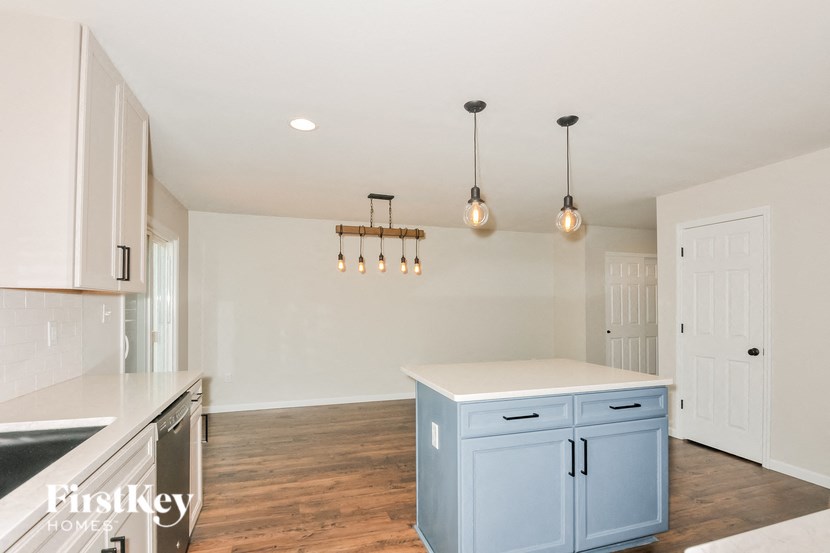 A kitchen with a blue island and pendant lights.