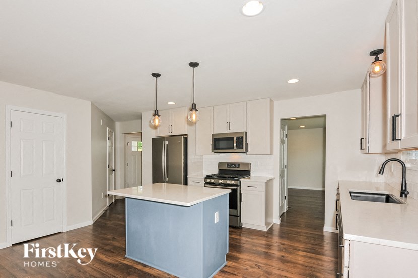 A kitchen with a blue island and white cabinets.