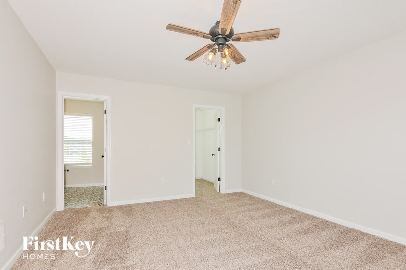 A spacious room with a ceiling fan and carpeted floor.