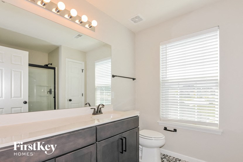 A bathroom with a white toilet and a mirror above a sink.